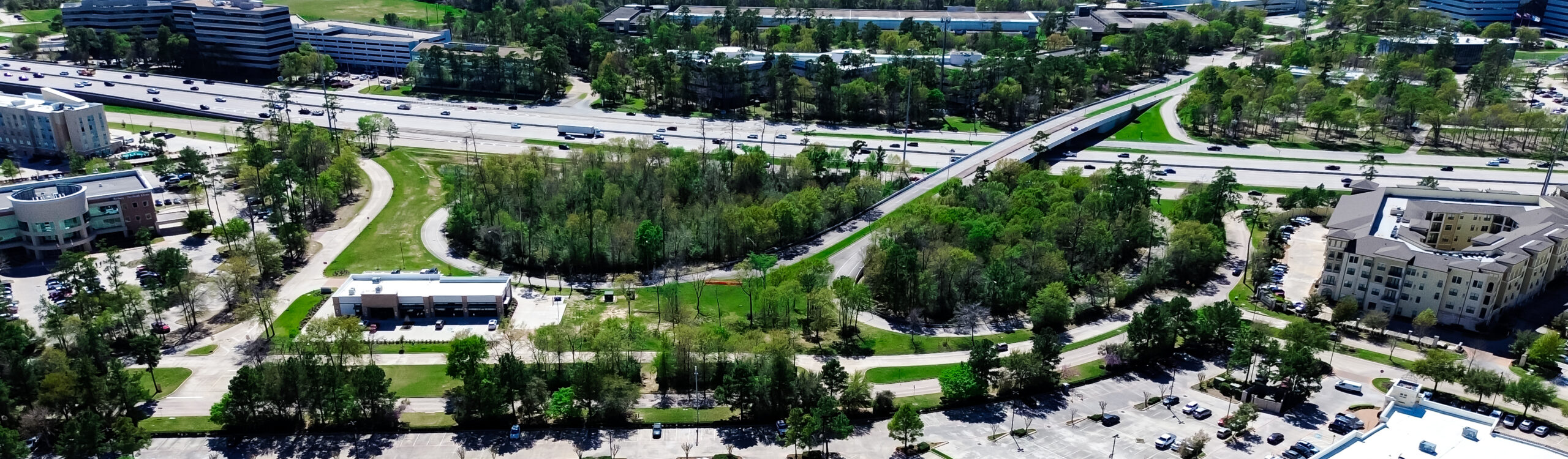 Aerial view of park with highway and buildings