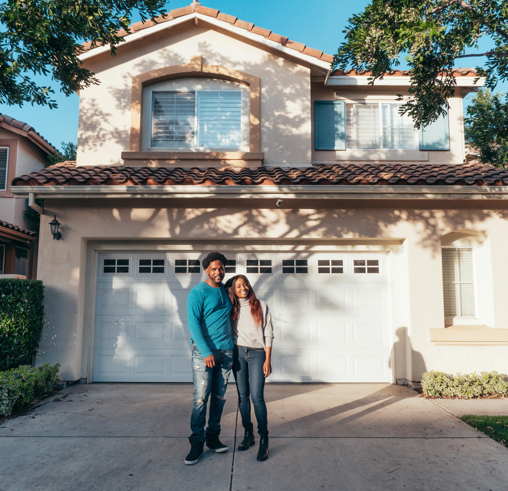 Smiling couple standing outside their suburban home