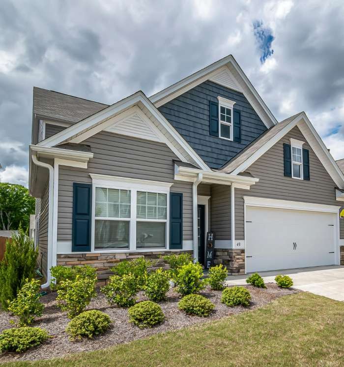 Gray two-story suburban house with shrubs