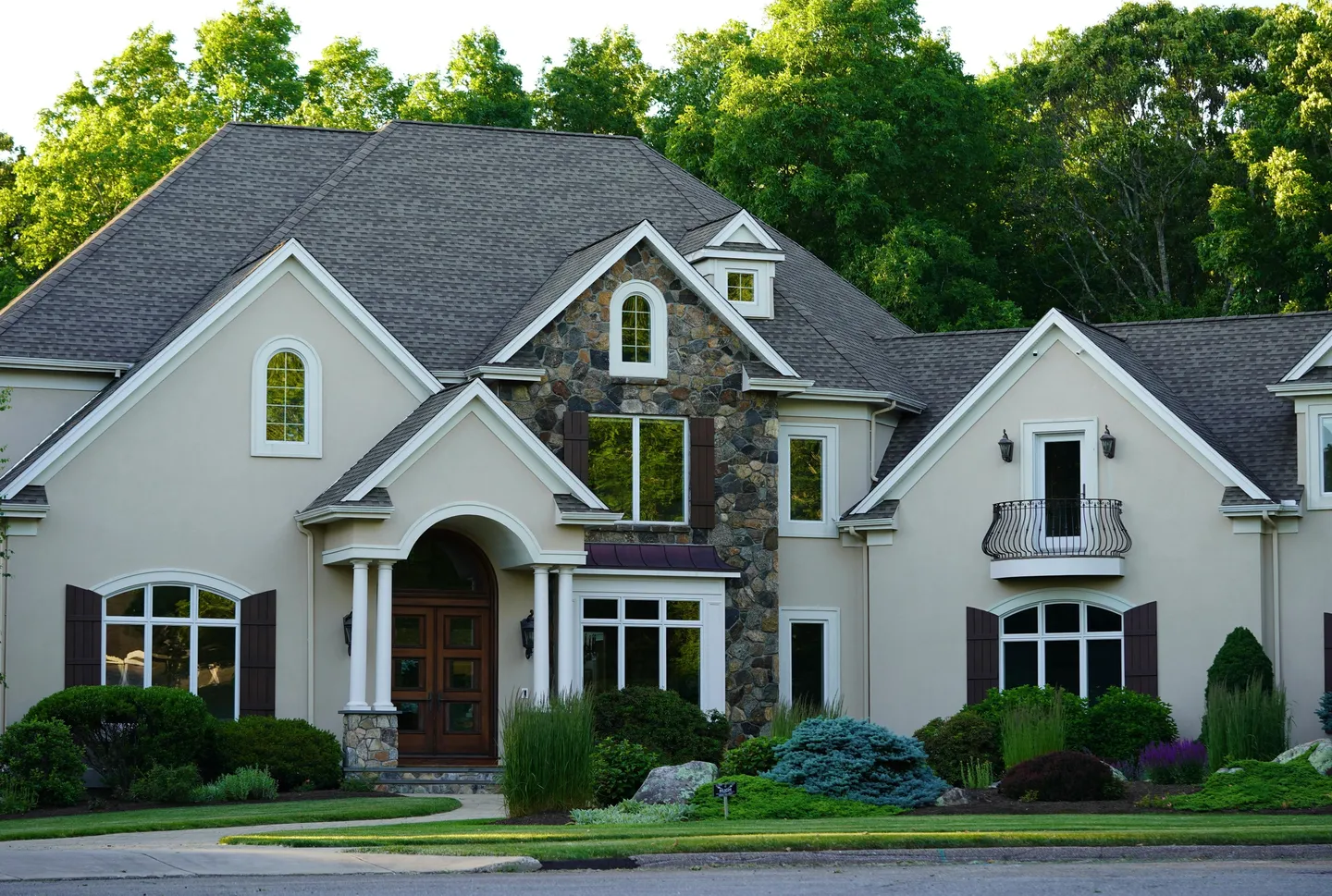 Large stone-accent luxury suburban house with landscaping